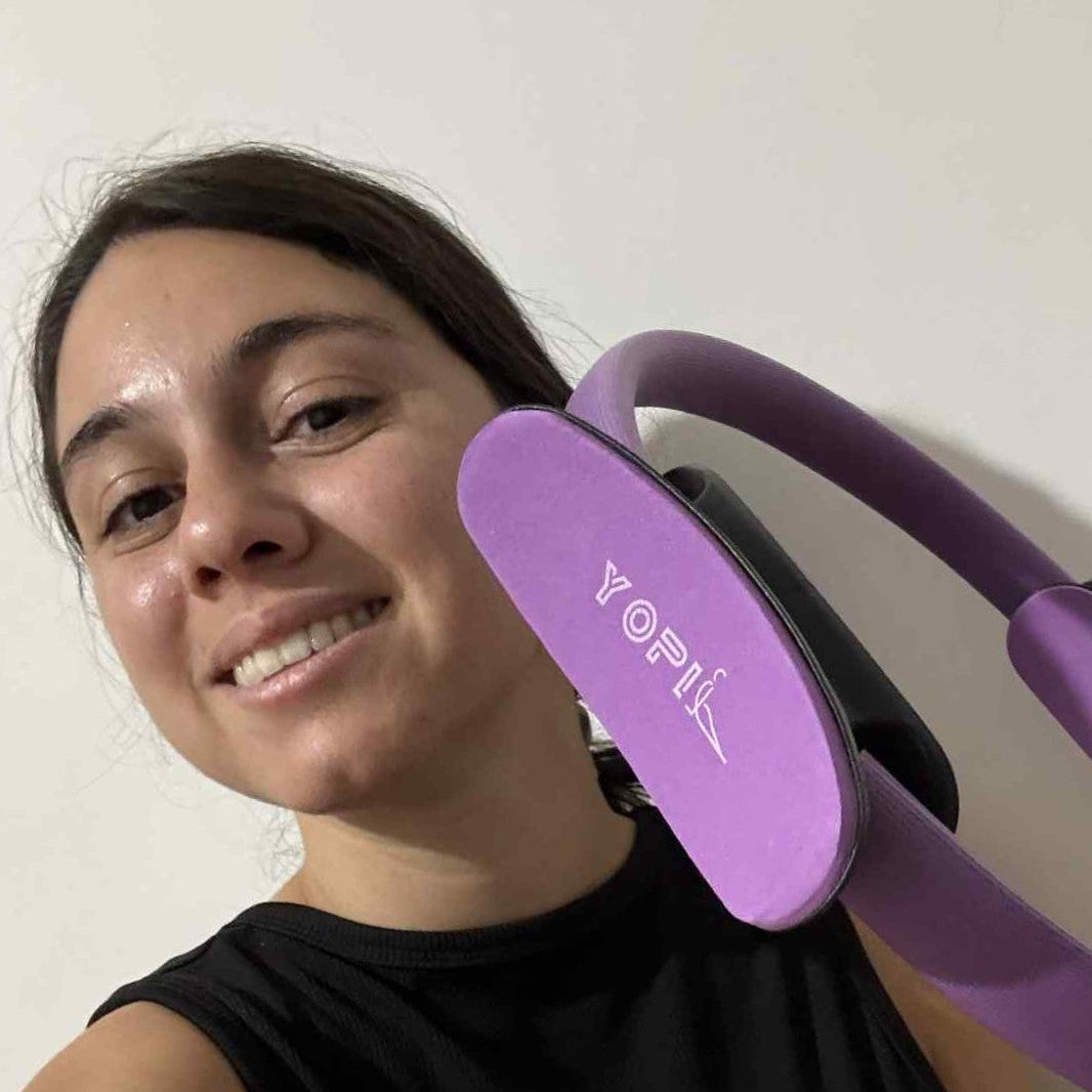 A woman holding a purple YOPIL Pilates exercise ring/circle against a plain background
